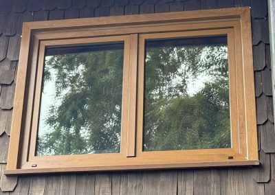 Ventana de PVC color madera en casa con revestimiento de tejuela