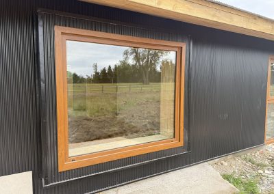 Ventanal fijo de PVC color madera en fachada negra