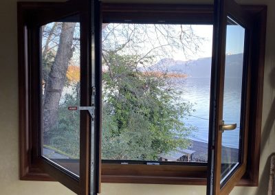 Ventana de PVC color madera abierta con vista al lago
