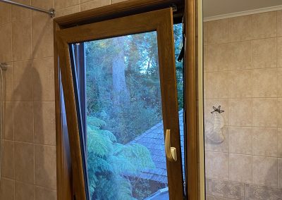 Ventana de PVC color madera abierta en modo oscilobatiente